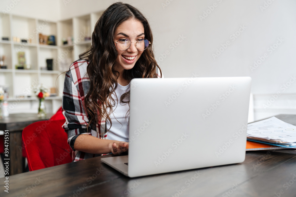 Happy nice woman smiling and working with laptop while sitting in cafe Happy nice woman smiling and working with laptop while sitting in cafe