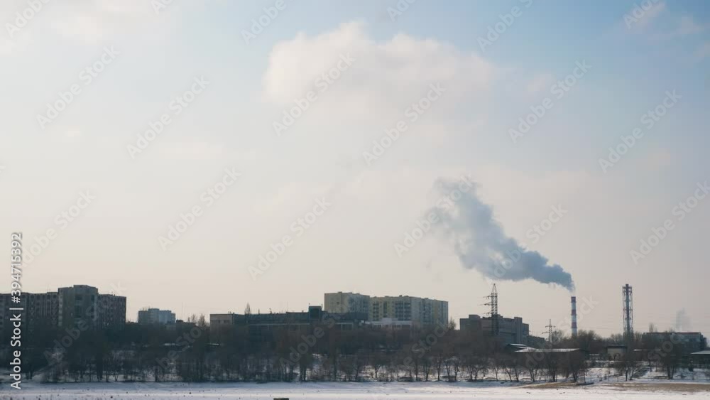 City in winter. The smoking pipe of the power plant rises among the houses. CHP heats houses City in winter. The smoking pipe of the power plant rises among the houses. CHP heats houses