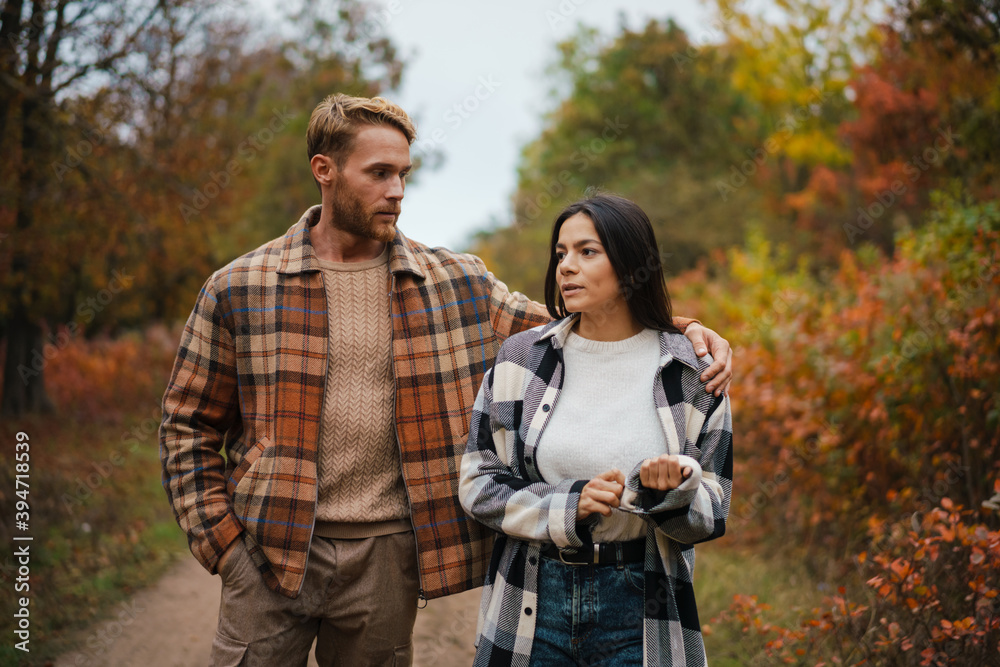 Serious couple talking and hugging while strolling in forest Serious couple talking and hugging while strolling in forest