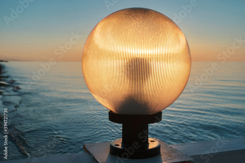 Sunlight shines through a lamp on the pier  beautiful sunset sky and sea background