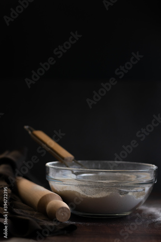 Bakery items - flour and eggs on dark background, healthy basic baking ingredients. Space for text