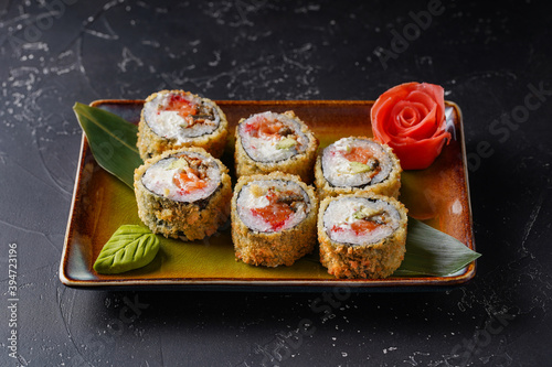 Roll with eel, avocado, salmon, cream cheese, tempura, Panko breadcrumbs. On dark background.