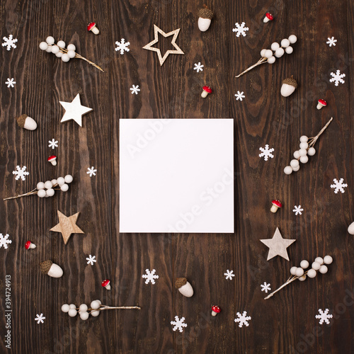 Holiday card - Christmas decorations and empty white frame on dark wooden background.