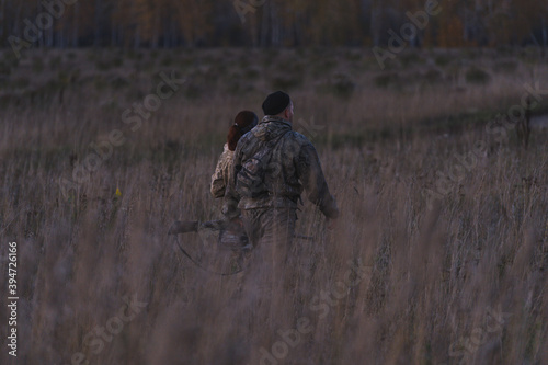 Hunters with guns go hunting. Two hunters cross the field into the forest in search of animals. Wildlife hunting for active people