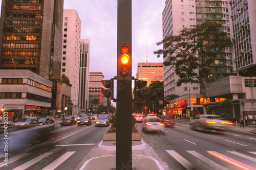 Paulista Avenue in São Paulo, Brazil. Movement of cars in the late afternoon. In the middle of the avenue, a traffic light, buildings and a pedestrian crossing in perspective.