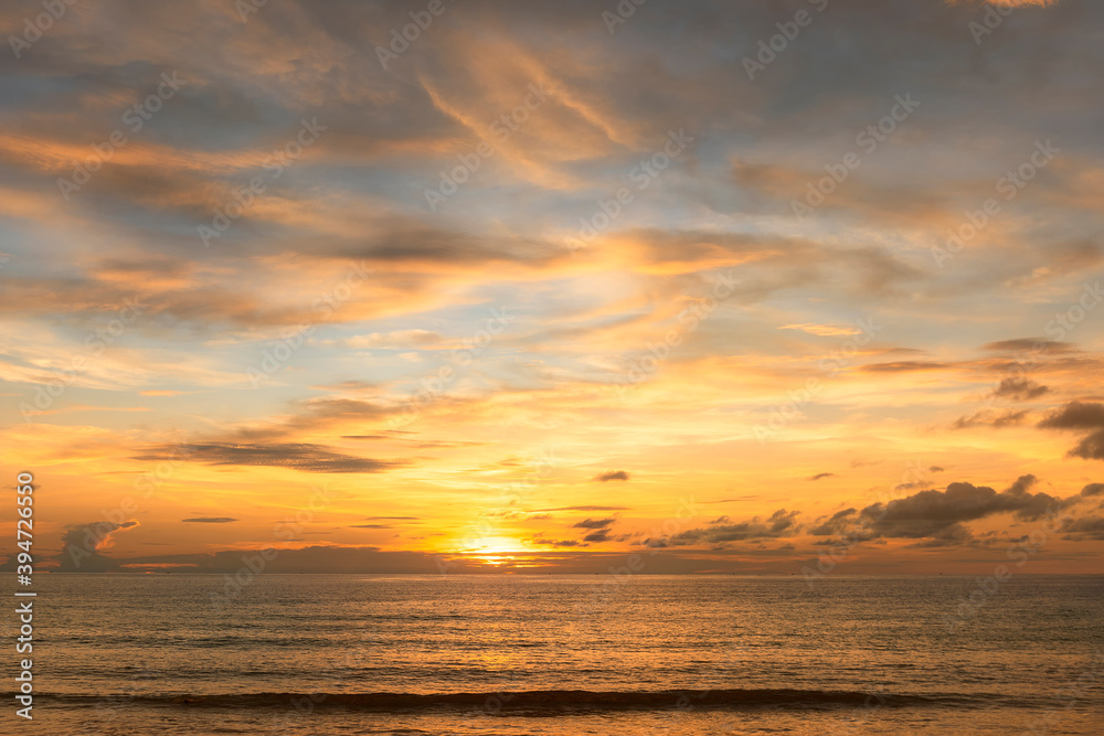 Beautiful sunset over the clam sea with cloud and sky background. Sunset over tropical beach. Nature summer  concept. Peak sunset over sea with yellow light reflect in cloud.