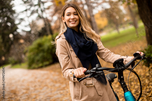 Young woman with electric bicycle in the autumn park