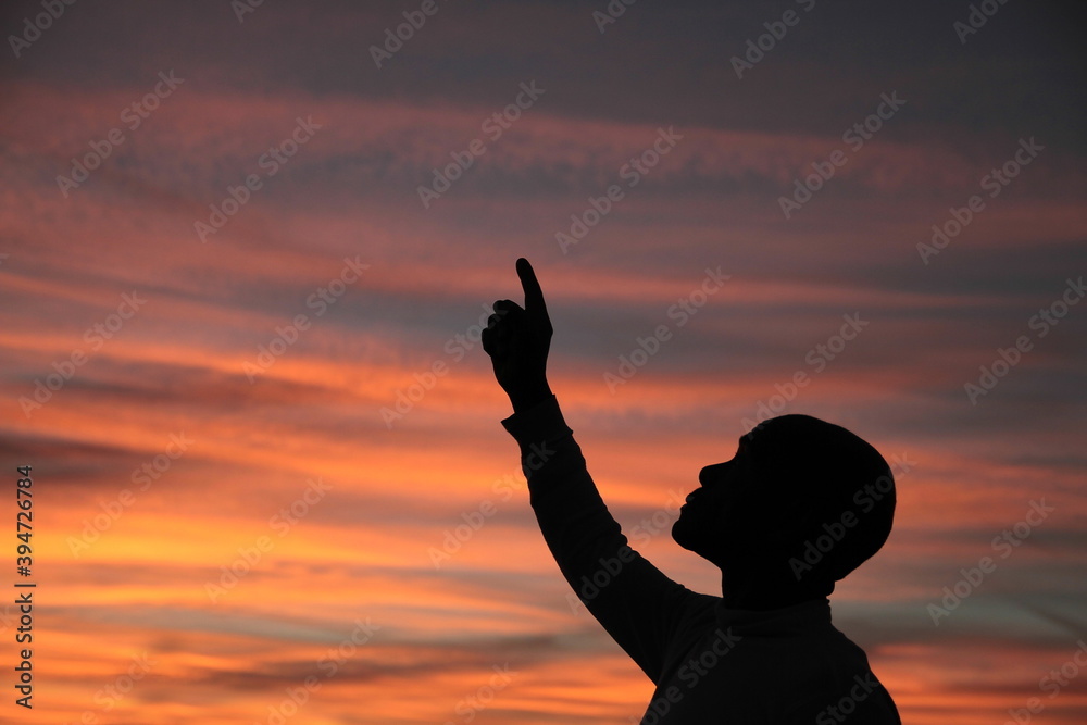 praying to god with arms outstretched in the sky sunset stock photo