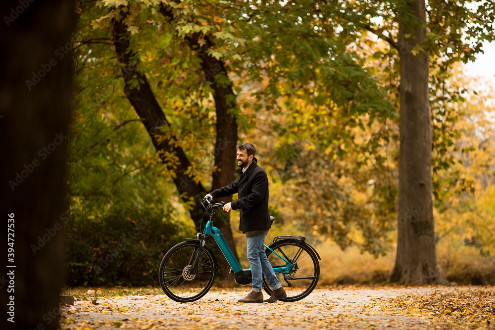 Young man with electric bicycle in te autumn park