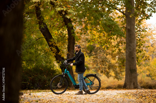 Young man with electric bicycle in te autumn park