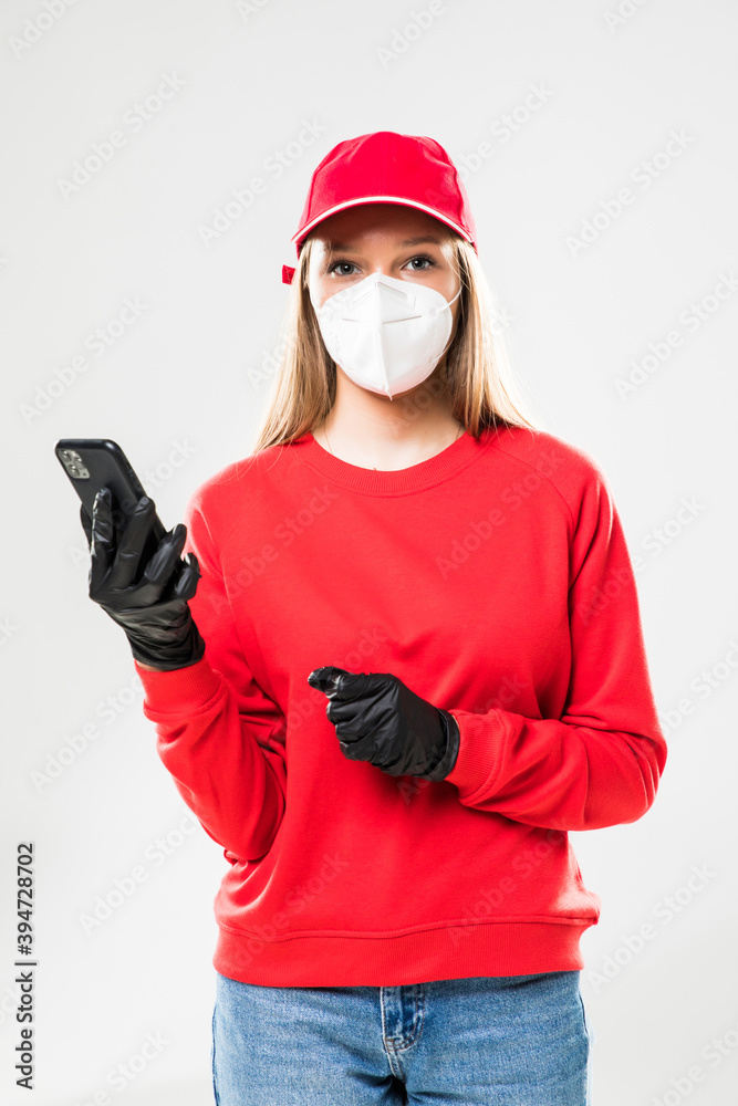 Delivery employee woman in red cap blank t-shirt uniform protect face mask gloves work courier service during quarantine coronavirus covid-19 virus hold pone isolated on white background Delivery employee woman in red cap blank t-shirt uniform protect face mask gloves work courier service during quarantine coronavirus covid-19 virus hold pone isolated on white background