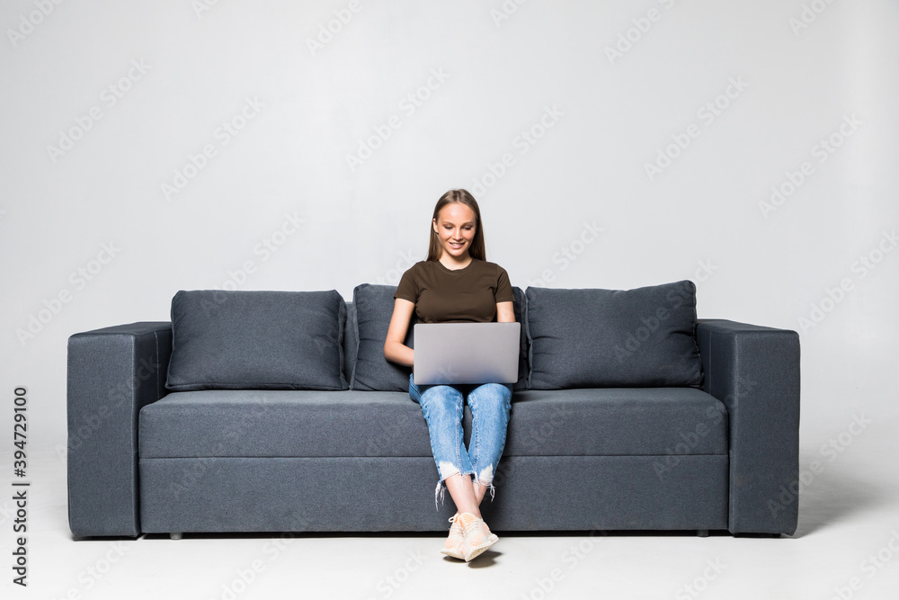 A pretty woman wearing casual clothes with laptop sit on sofa isolated on white background A pretty woman wearing casual clothes with laptop sit on sofa isolated on white background