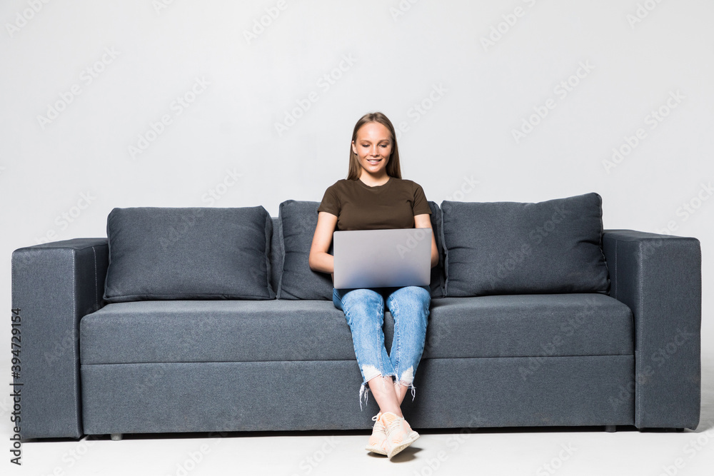 A pretty woman wearing casual clothes with laptop sit on sofa isolated on white background A pretty woman wearing casual clothes with laptop sit on sofa isolated on white background