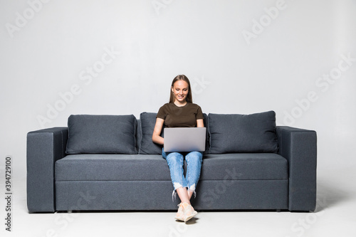 A pretty woman wearing casual clothes with laptop sit on sofa isolated on white background