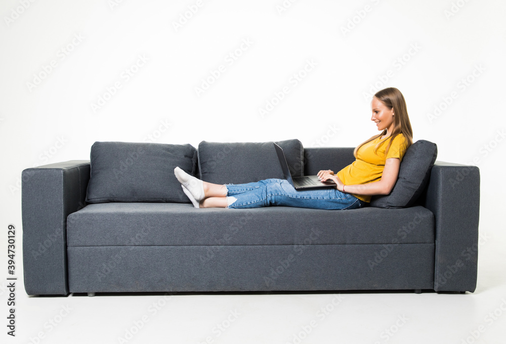 Woman lying on sofa at home working on laptop isolated on white background. Woman lying on sofa at home working on laptop isolated on white background.