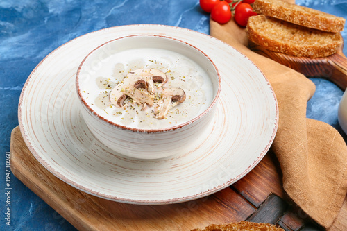 Bowl of tasty mushroom cream soup on color background