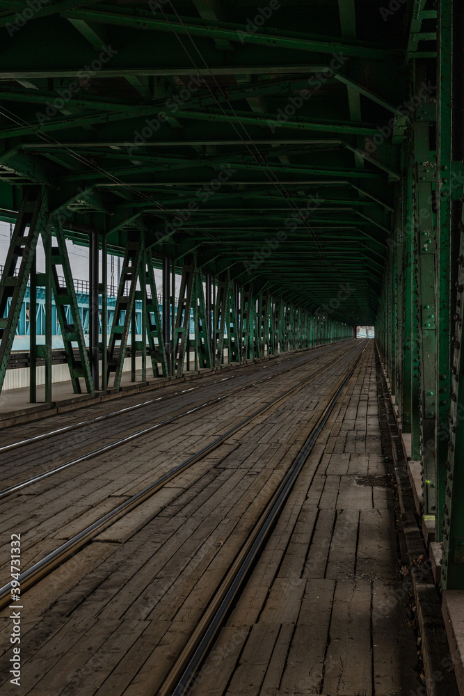 Obraz premium Long wooden and metal bridge with tram rails and green construction