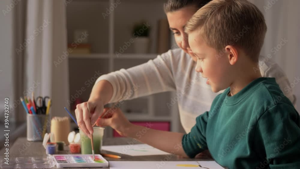 family, leisure and people concept - mother and little son with colors and paper drawing at home family, leisure and people concept - mother and little son with colors and paper drawing at home
