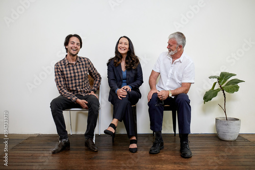 Three professional business people sitting in a row in a studio photo