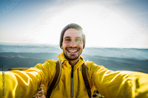 Happy hiker taking a selfie on the top of a mountain - Smiling man smiling looking camera - Handsome male face outdoor