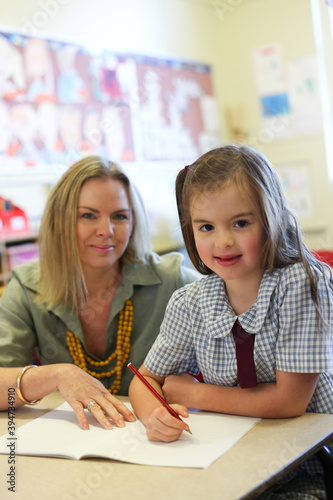 School teacher helping child with her writing work