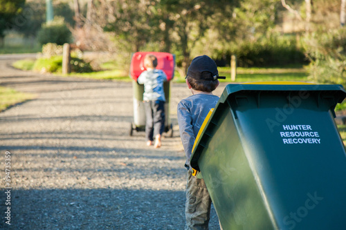 Young boy doing job taking bin across the road photo