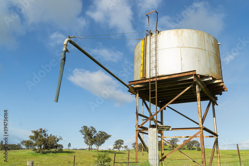 A water tank sitting on a high metal stand in a paddock photo