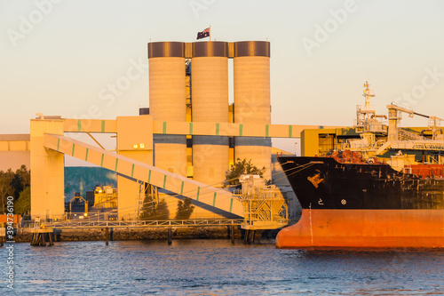 The bow of a ship docked near tall grain silos at the Port of Brisbane photo