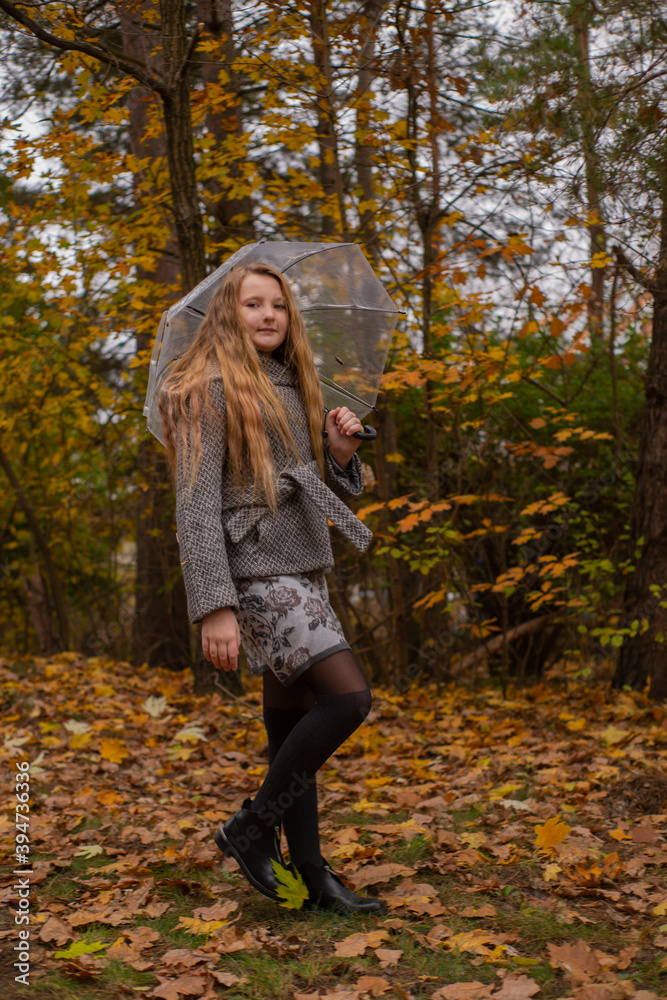 cute beautiful teenage brunette girl in grey coat walking with a transparent umbrella. Cosiness, autumn
