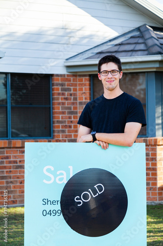Young man with sold sign and first home