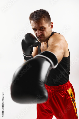 Aggressive boxer in black boxing gloves punching isolated on white background.