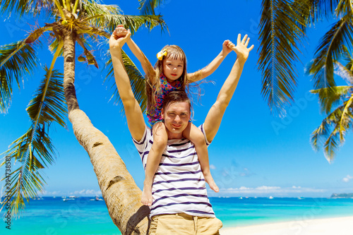 Dad and little daughter have fun on a coconut tree on a sandy tropical beach. The concept of travel and family holidays.