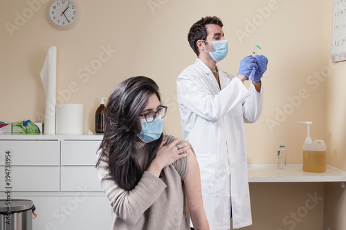 Woman wearing surgical mask waiting for the doctor to vaccine him on a clinic. 