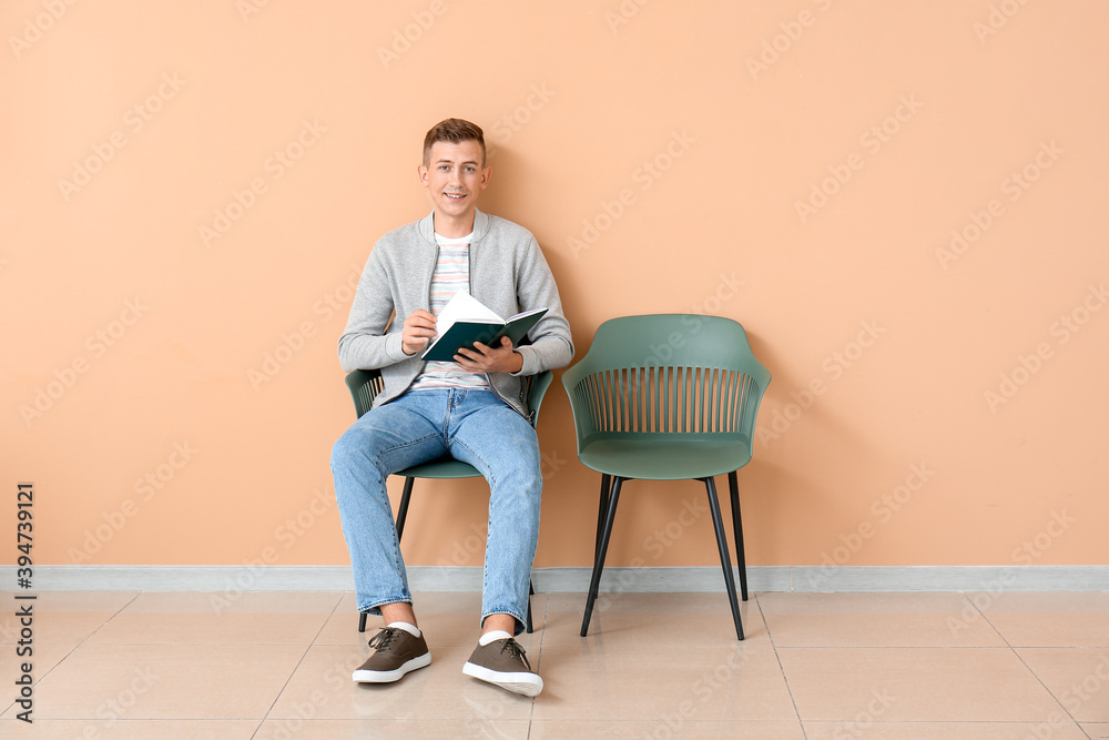 Young man reading book near color wall Young man reading book near color wall