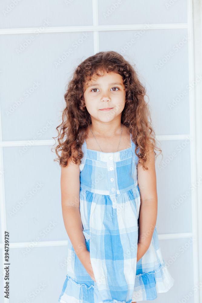 Portrait of a beautiful little curly girl in a blue dress