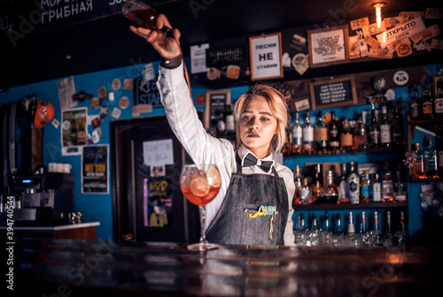 Girl barman creates a cocktail on the alehouse