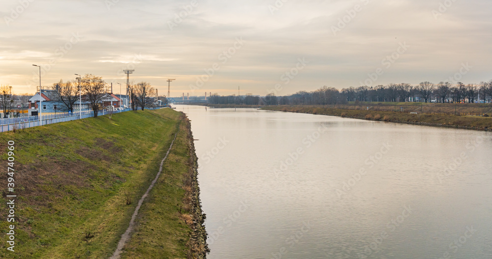 Long green coast near Odra river with few trees and buildings