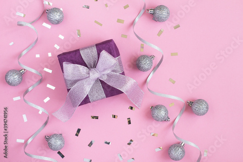 Top view of Christmas gift with silver bow on the pink background