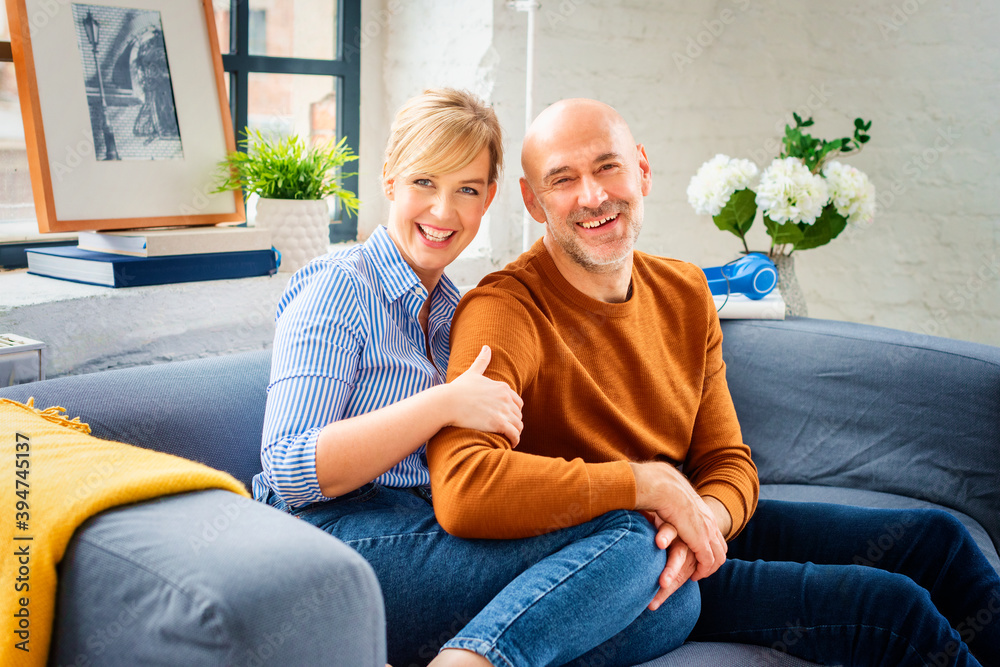 Shot of happy couple sitting on couch at home and bonding to each other while relaxing at home.