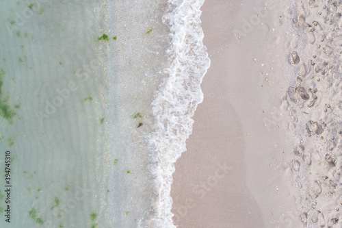 A coastal wave runs over a sandy sea beach. The view from the top. Motion blur.