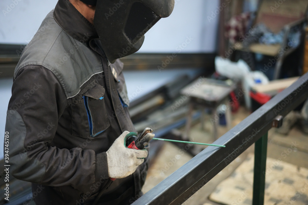 Photo of a welder working in a mask on a metal table in a workshop Photo of a welder working in a mask on a metal table in a workshop