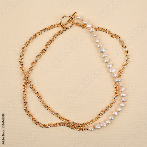 Luxury elegant baroque pearl and golden necklace on beige textured background