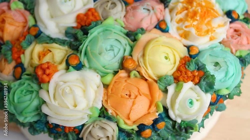 The cake is decorated with realistic edible cream flowers of roses, Ranunculus, peonies and Rubus chamaemorus, extreme close-up, high angle, real time, pastry Floristics, the object rotates in the fra