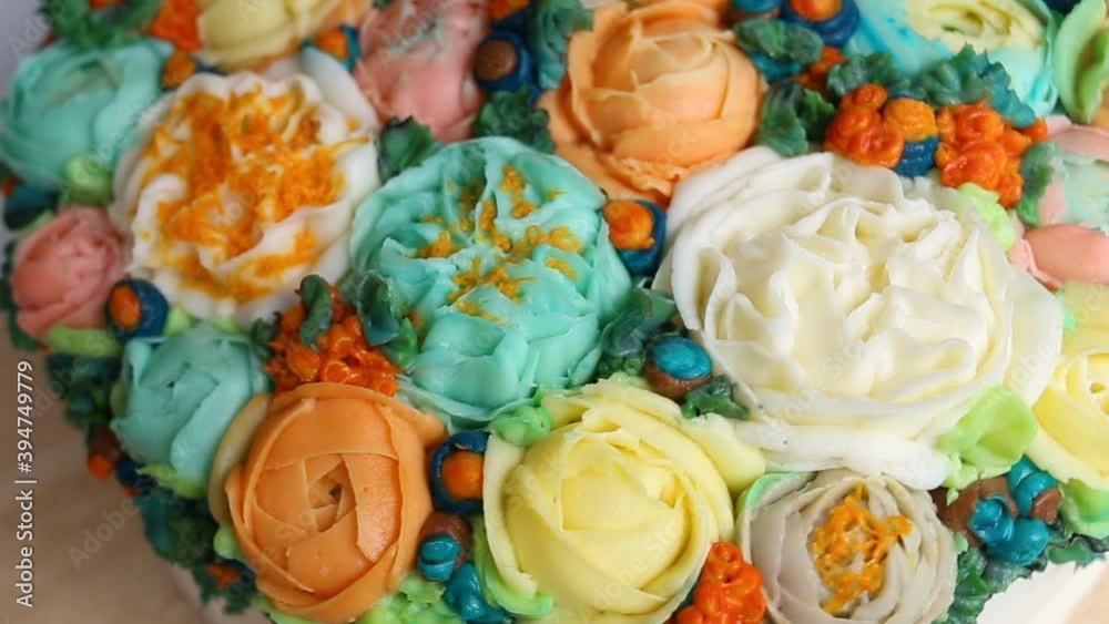 Handmade cake decorated with realistic edible cream flowers of roses, Ranunculus, peonies and Rubus chamaemorus, extreme close-up, high angle, real time, pastry floristry, object rotates in the frame Handmade cake decorated with realistic edible cream flowers of roses, Ranunculus, peonies and Rubus chamaemorus, extreme close-up, high angle, real time, pastry floristry, object rotates in the frame