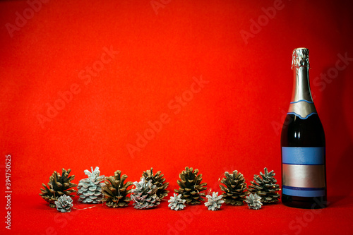 New Year and Christmas card on a red background. Spruce silver and natural cones with Christmas garlands and a bottle of champagne. Minimalism concept. Content for the designer. photo