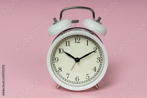 Retro alarm clock on pink background. Old fashioned alarm clock