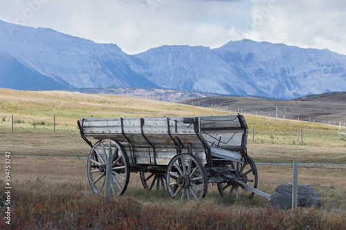 Old and decaying farming wagon sits alone in a field on the eastern edge of the Rocky Mountains in rural Alberta