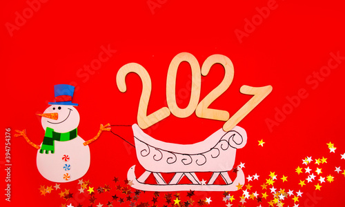 New year s composition in 2020. Stylish decor concept  Christmas snowman with paper sleigh on red background. Flat bed  top view  postcard Background