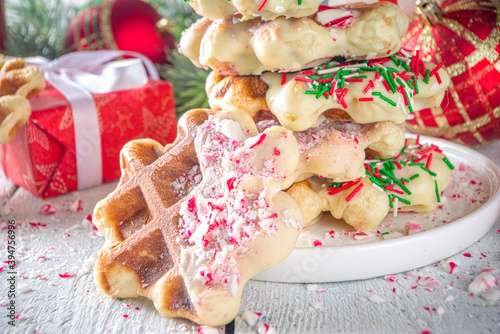 Stack of homemade Belgian waffles for Christmas breakfast. Traditional waffles dipped in white chocolate, with Candy Cane crumbs and festive sugar sprinkles