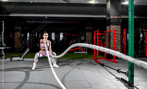 Young woman in professional gym performing exercises with combat ropes. Healthy lifestyle concept © александр таланцев